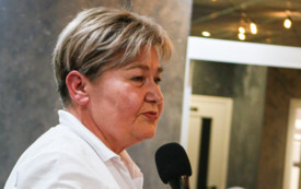 Kobieta w białej koszulca trzymająca w ręku mikrofon