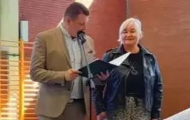 Kobieta w czarnej kurtce uśmiechnięta i mężczyzna obok stojący 