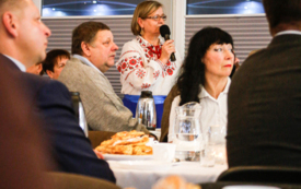 Kobieta w białej bluzce w kwiaty trzymająca mikrofon w ręku