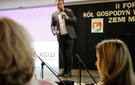 Mężczyzna w garniturze trzymający mikrofon w ręku