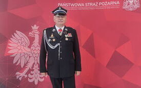 Na zdjęciu na czerwonym tle strażak w mundurze. Na tle biały napis Państwowa Straż Pożarna i godło Polski.