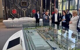Na zdjęciu grupa przedstawicieli firm i samorząd&oacute;w oglądających makietę budynku.