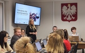 Na zdjęciu uczestnicy szkolenia. Przed każdym laptop. Na ścianie, na ekranie wyświetlana prezentacja.