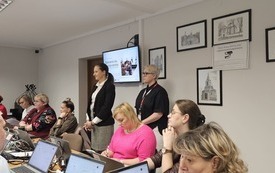 Na zdjęciu uczestnicy szkolenia oraz trenerki. Przed każdym laptop. Na ścianie, na ekranie wyświetlana prezentacja.