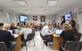 Na zdjęciu uczestnicy szkolenia. Przed każdym laptop. Na ścianie, na ekranach wyświetlana prezentacja.