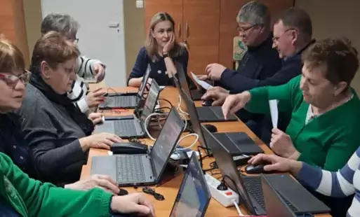 Kobiety i mężczyźni siedzący przy stolikach przy, których są laptopy.