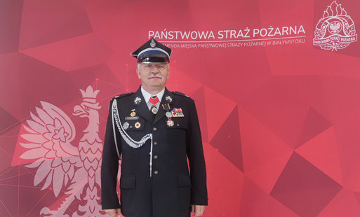 Na zdjęciu na czerwonym tle strażak w mundurze. Na tle biały napis Państwowa Straż Pożarna i godło Polski.